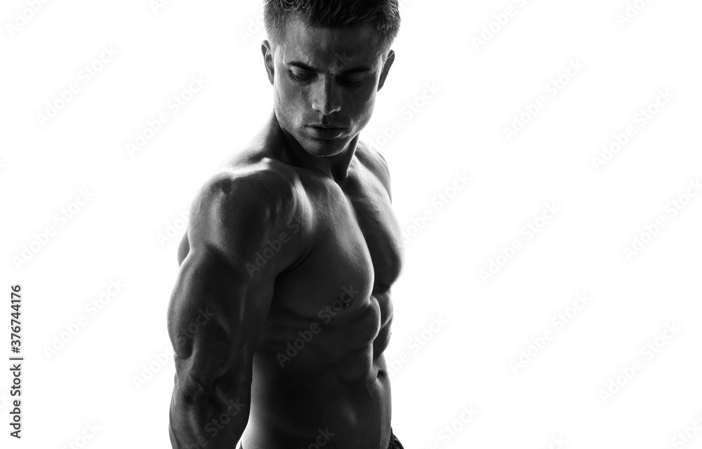 Muscular model sports young man on white background. Black and white fashion portrait of strong brutal guy. Sexy torso. Male flexing his muscles. - obrazy, fototapety, plakaty 