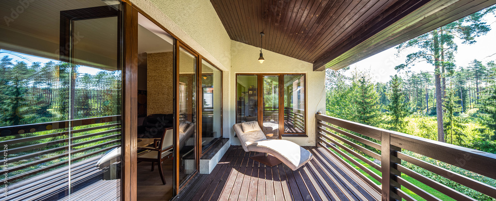 Modern wooden terrace in luxury cottage. Panorama windows. Soft lounge chair. - obrazy, fototapety, plakaty 
