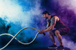 © zamuruev - Bearded athletic looking bodybulder work out with battle rope on dark studio background with smoke. Strength and motivation.