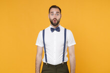 Shocked Amazed Young Bearded Man 20s Wearing White Shirt Bow-tie Suspender Posing Keeping Mouth Open Saying Wow Looking Camera Isolated On Bright Yellow Color Wall Background, Studio Portrait.