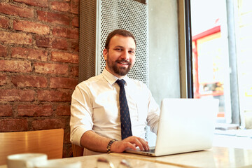 The employee sitting outside the office continues to work outside. man working in the office with white shirt and tie.