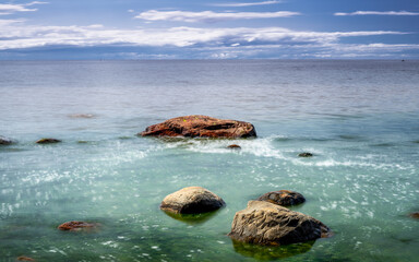 Marine landscape of coastal rocks in calm, silky water. Long exposure.