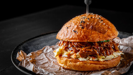 Traditional barbecue pulled beef burger with vegetables on dark background