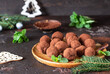 © valentinamaslova - Dark chocolate truffles with raw cocoa powder, mint and fir tree branches, dark brown stone background. Christmas composition.