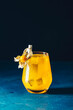 Yellow orange cocktail with tangerine and rosemary in glass decorated Physalis peruviana on dark blue concrete background , close up. Christmas and New Year holiday welcome drink