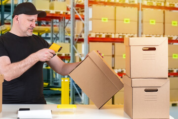 Poster - Working in a warehouse. A man with a barcode reader in the warehouse. Preparing boxes with orders to send. Warehouse logistics.