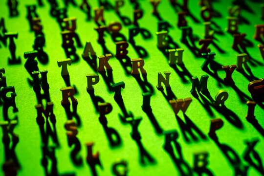Latin letters stand on a green background and cast shadows. The letters of the alphabet in random order. The concept of Literacy on a green background. Latin characters with focus in the center.