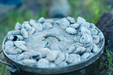 Close Up Of Charcoals Cooking Food In Dutch Oven