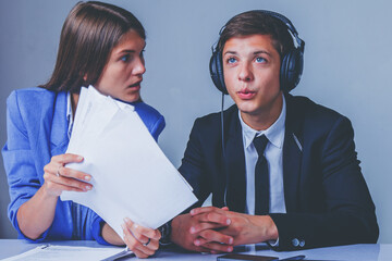 Portrait of young female team leader aggressive attacks male employee working in office. Horizontal image.