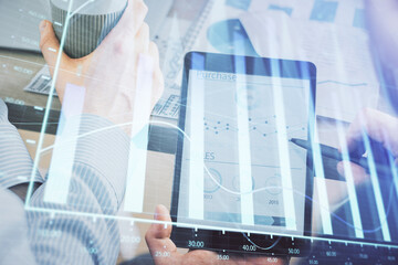 Double exposure of man's hands holding and using a phone and financial chart drawing. Market analysis concept.