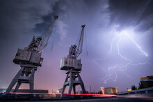 Low Angle View Of Cranes With Lightning In Sky At Night