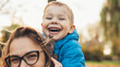 Close up photo of a caucasian mother and son with glasses playing outside in the park