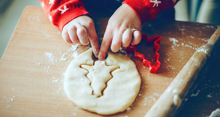 Christmas preparation of a young kid making cookies at home wearing red sweater