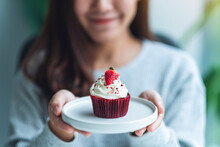 A Beautiful Asian Woman Holding A Plate Of Red Velvet Cup Cake