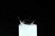 Splash from ice cube in a glass of water, isolated on the black background