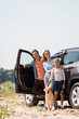 Selective focus of family with golden retriever looking at camera while standing near car outdoors