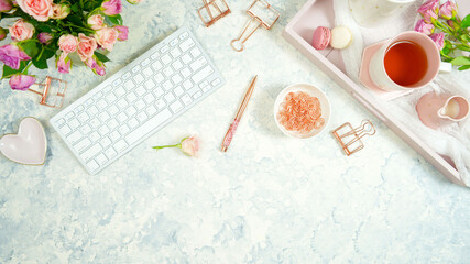 Wall Mural - Blush pink theme cosy hygge desktop workspace with keyboard smart phone tea and rose on a stylish white marble textured background. Top view blog hero header creative flat lay. Negative copy space.