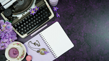 Wall Mural - Purple theme vintage writers desktop workspace with typewriter, lavendar tea, hibiscus flowers and old books on stylish purple textured background. Top view blog hero header creative flat lay.