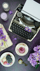 Wall Mural - Purple theme vintage writers desktop workspace with typewriter, lavendar tea, hibiscus flowers and old books on stylish purple textured background. Top view blog hero header creative flat lay.