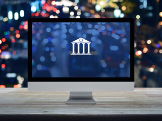 Bank flat icon on desktop modern computer monitor screen on wooden table over blur colorful night light traffic jam road in city, Business banking online concept