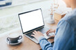 © panitan - computer mockup blank screen.hand woman work using laptop with white background for advertising,contact business search information on desk at coffee shop.marketing and creative design