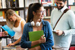 © NDABCREATIVITY - Group of happy college students studying at campus library together