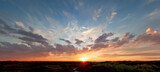 Fototapeta Zachód słońca - Panoramic view, beautiful sunset over the dunes, heavy clouds and sunset with sun rays, blue orange sky, sun in the middle, texel, Island