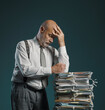 © stokkete - Pensive businessman leaning on a pile of paperwork