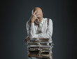 © stokkete - Pensive businessman leaning on a pile of paperwork