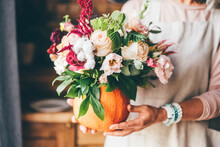 Pumpkin With Beautiful Bouquet Of Flowers In Woman Hands.