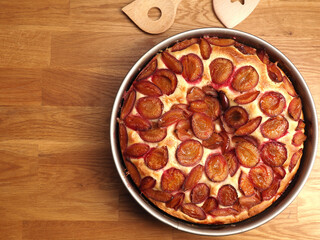 Delicious plum cake made from organic ingredients in a baking pan on a rustic kitchen table