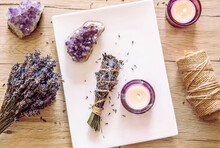 Homemade Herbal Lavender (lavendula) Smudge Stick Smoldering On White Plate With Candles And Amethyst Crystal Clusters For Decoration. Spiritual Home Cleansing Concept.