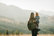 © Serhii - Mother and child with a backpack enjoying the sunset in the mountains.The concept of family travel, adventure, and tourism.  Lifestyle and hiking autumn vacations outdoor. Back view.