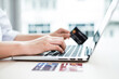 © Orathai - The businesswoman's hand is holding a credit card and using a laptop for online shopping and internet payment in the office
