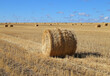 Mown wheat. Haystack on a field against a blue sky with clouds.Large pile of densely packed hay