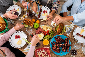 Wall Mural - Family friends have fun together in winter eating food on a wooden table - vertical top view and concept of friendship and caucasian people enjoying celebration at home or restaurant