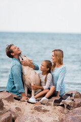 Wall Mural - Selective focus of man embracing golden retriever near family on beach