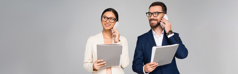 Wall Mural - panoramic concept of interracial businesspeople talking on mobile phones while holding folders isolated on grey