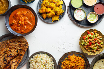 Wall Mural - Variety of Indian food, different dishes and snacks on white rustic background. Pilaf, butter chicken curry, rice, palak paneer, chicken tikka, dal soup, naan bread, assortment of chutney. Top view.