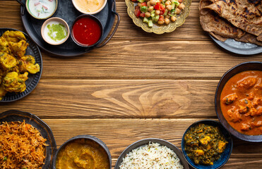 Wall Mural - Assorted Indian home food, different dishes and snacks, wooden rustic table. Homemade Pilaf, butter chicken curry, palak paneer, chicken tikka, dal soup, naan bread, choice of chutney. Space for text.