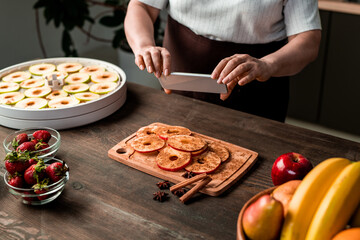 Wall Mural - Close-up of unrecognizable woman using smartphone while photographing stage of cooking healthy snacks, blogging concept