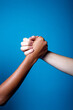 Black and white women hands handshake showing each other friendship and respect on blue background - Isolated diverse multiethnic female hands supporting