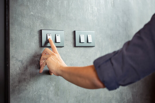 The young man's hand turned off the light switch. Energy saving concept