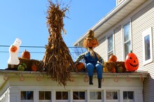 Roof Of A House Decorated For Halloween With Corn, Pumpkins, Scarecrows And A Ghost