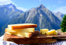 Cheese Collection, French Comte, Beaufort Or Abondance Cow Milk Cheese Served Outdoor With Alps Mountains Peaks On Background