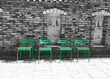 Zielone metalowe krzesła na tle czarno-białego ceglastego muru. Śródziemnomorska sceneria.