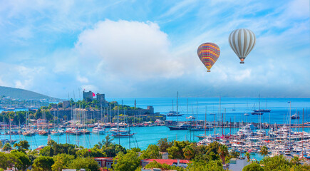 Wall Mural - Hot air balloon flying over Saint Peter Castle (Bodrum castle) and marina, amazing white clouds in the background  - Bodrum, Turkey