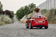 A Girl Riding A Toy Car
