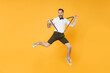 © ViDi Studio - Full length portrait of crazy screaming young bearded man 20s wearing white shirt shorts posing jumping stretching suspender looking camera isolated on bright yellow color wall background studio.