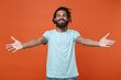 © ViDi Studio - Cheerful young african american man guy in blue casual t-shirt posing isolated on bright orange wall background studio portrait. People sincere emotions lifestyle concept. Reach out stretch hands.